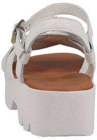 Białe sandały na platformie z wieloma paskami, górą z gładkiej skóry i teksturowaną jasnobrązową wkładką. Posiadają złotą dekorację w postaci klamry.