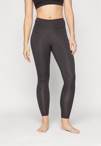 Leggings noirs taille haute avec un motif texturé, coupe ajustée et tissu doux, conçus pour le confort et la flexibilité lors des mouvements.