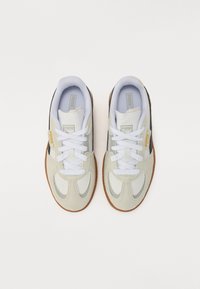 Scarpe da ginnastica grigio chiaro e bianche realizzate in materiali scamosciati e in rete, con suola in gomma, lacci bianchi e piccoli dettagli con logo.