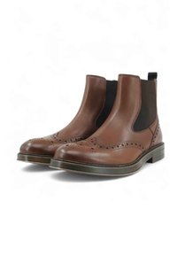 Stivaletti Chelsea in pelle marrone con dettagli brogue, pannelli elastici laterali neri e tacchi bassi impilati su sfondo bianco.