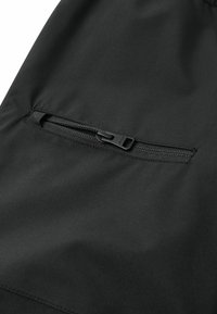 Schwarze Sportshorts mit einer glatten Textur und einer sicheren Reißverschlusstasche an der Seite zur Aufbewahrung. Das Material ist leicht und langlebig.