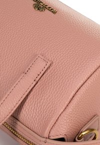 Borsa in pelle rosa con finitura testurizzata, caratterizzata da un logo dorato e una cerniera. Include una tracolla piatta e dettagli dorati sulle parti metalliche.