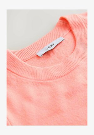 Korallszínű pulóver bordás nyakkivágással, puha textúrával és egy "NEXT" feliratú címkével az belső nyakrészen.