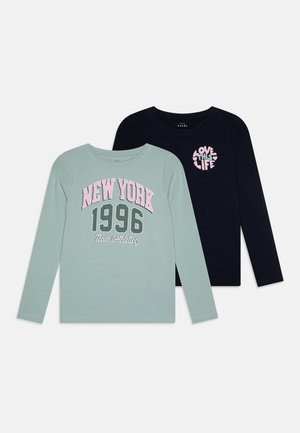 Twee lange mouwen t-shirts: een mintgroen met "New York 1996 Team Athletics" in roze, en een marineblauwe met "Love This Life" in roze harten.