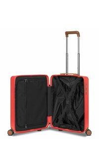 Hard-shell suitcase in vibrant red with a brown handle. Interior features black fabric lining, a zipped pocket, and cross straps for securing items.