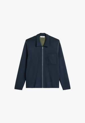 Marineblauwe jas met ritssluiting, kraag, groene voering, voorzak en contrasterende stikseldetails. Zachte, gestructureerde stof.