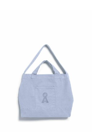 Hellblaue Segeltasche mit Fronttasche und einem aufgedruckten dunkelblauen schlüssellochförmigen Symbol, mit kurzen Griffen und einem längeren Schulterriemen.