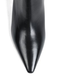 Czarny but w szpic wykonany z teksturowanej skóry. Gładkie wykończenie, wąska sylwetka oraz brak widocznych elementów metalowych czy ozdób.