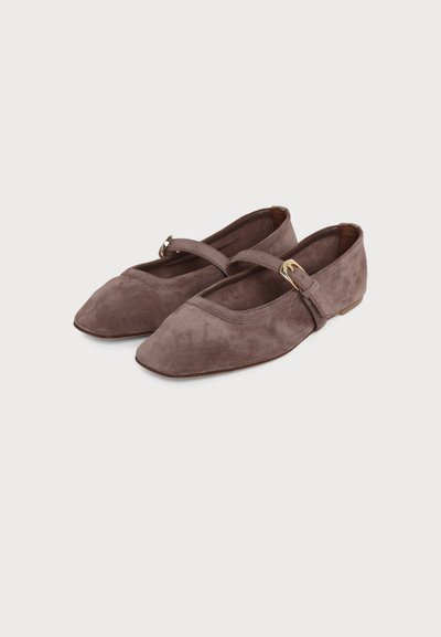 Ballerines Mary Jane en daim marron avec bouts carrés et brides latérales ajustables avec boucles dorées sur fond uni.