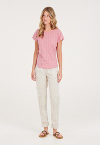 Blusa corta de manga corta con estampado rojo, combinada con pantalones cargo beige claros y sandalias marrones. La blusa presenta un diseño de cuadrícula texturizada.