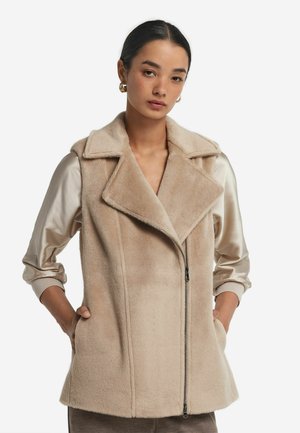 Beige konstgjord päls väst med notched krage, dragkedja framtill och sidofickor. Har en mjuk textur och skräddarsydd passform.