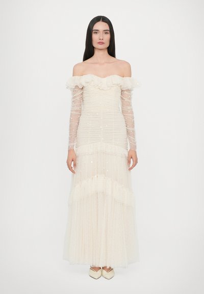 Off-shoulder long dress with gathered ivory fabric, ruffled neckline, sheer long sleeves, and scattered sequins. Textured layers at the hem.