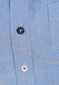 Lichtblauw katoenen shirt met een gestructureerde weving. Voorzien van zwarte en witte knopen, één borstzak en nette stiksels.