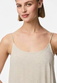 Haut sans manches de couleur beige clair avec un décolleté rond et des bretelles fines. Le tissu a une apparence texturée, semblable à du lin.