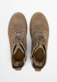 Bottines en daim marron avec un design à bout rond, lacets beiges et semelle en caoutchouc texturé. Équipées de zippers sur les deux côtés pour un enfilage facile.