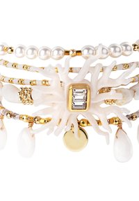 Weißes Korallenarmband mit goldenen Akzenten, das Perlen, geometrische Details und glatte, tropfenförmige Anhänger aufweist. Mehrere Stränge sind sichtbar.