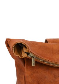 Brown leather bag featuring a folded top, visible zipper, and a textured surface. Bronze hardware detail near the zipper.