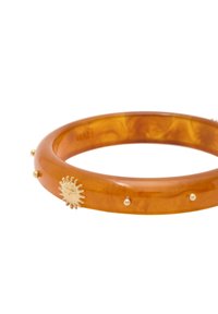 Acryl-Armband in Bernstein mit einer glatten Oberfläche. Es verfügt über ein goldenes Sonnensymbol und kleine goldene Akzente rund um das Band.