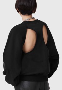 Felpa nera con un design a schiena scoperta. Caratterizzata da maniche lunghe e voluminose e una texture morbida. Accentuata con una collana a catena.