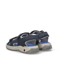 Sandalias azul marino con parte superior texturizada gris, correas de Velcro ajustables y una suela resistente beige con una plantilla azul y un patrón de tracción.