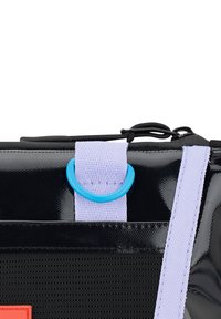 Svart väska med glänsande yta, som har ett lila band och en blå ringdetalj. Innehåller en röd rektangulär logotypdetalj.