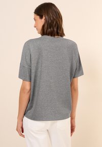 Grijze T-shirt met korte mouwen en een relaxte fit, gemaakt van een zachte stof, met een ronde hals en een naad aan de achterkant.