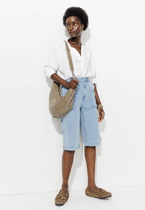 Chemise légère blanche à boutons, shorts bermuda en jean bleu, sac à épaule gris et chaussures à enfiler à motifs léopard. Textures lisses et coupe décontractée.