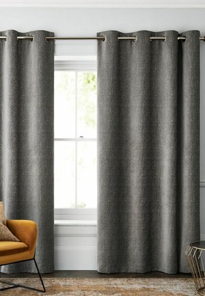 Gray textured curtains hang on a metal rod covering a window with white trim, next to a mustard chair and a round glass-top side table.