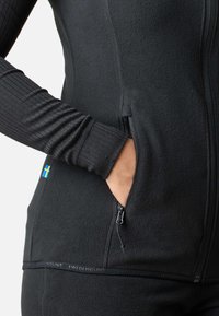 Sort fleece jakke med ribbede ærmer, sidelomme med lynlås og "Swedemount" logo på kanten. Har et svensk flag etikette.