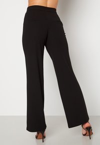Zwarte wijde broek met een soepele textuur, hoge taille en zakdetails. Heeft rechte randen en een comfortabele pasvorm.