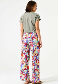 Top gris de manga corta combinado con pantalones de pierna ancha multicolores que presentan un patrón floral abstracto. Tejido de textura suave con un ajuste relajado.