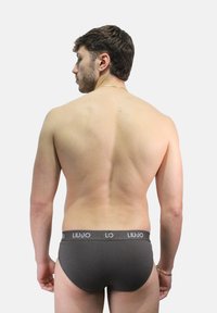 Slip grigi LIU JO con texture liscia e fascia elastica con dettagli del logo, mostrati da dietro su un torso nudo.