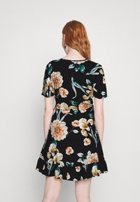 Musta lyhythihainen mekko, jossa on oranssia, valkoista ja vihreää kukkakuosia. Mekossa on levenevä helma ja pyöreä kaula-aukko.