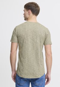 Olivengrøn, meleret kortærmet t-shirt med rund halsudskæring og bøjet fald. Blød stofstruktur, synlige stikninger.