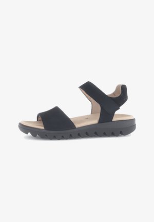 Zwarte sandalen met een brede teband, een verstelbare enkelband en een rubberen zool met textuur, voorzien van zigzagpatronen voor grip.