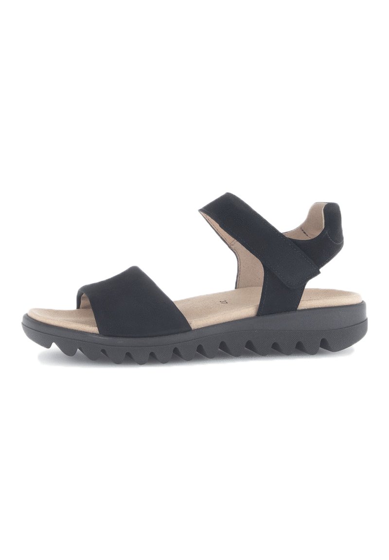 Zwarte sandalen met een brede teband, een verstelbare enkelband en een rubberen zool met textuur, voorzien van zigzagpatronen voor grip.