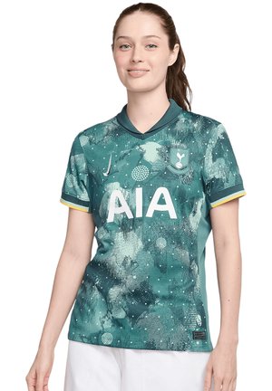 Maillot de football vert en tissu léger, avec un motif texturé, un logo "AIA" blanc et des accents jaunes sur les manches.