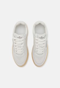 Hvite lær sneakers med perforerte detaljer, kontrasterende grå søm, hvite snøringer og lysebrune gummisåler. Merkeetikett på tungen.