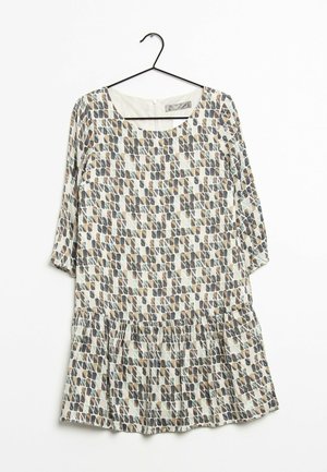 Sukienka z rękawami do łokcia i obniżoną talią, z geometrycznym wzorem w odcieniach beżu, szarości i bieli, wisząca na czarnym wieszaku.
