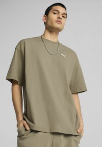 Olivovo zelené oversize tričko vyrobené z mäkkej bavlny s krátkymi rukávmi. Obsahuje malé biele logo Puma na ľavej hrudi.