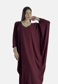 Bordeaux, oversized kaftan lavet af struktureret stof, med V-halsudskæring og brede, svajende ærmer, der falder yndefuldt.