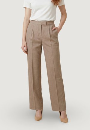 Donna che indossa pantaloni beige a vita alta con gamba dritta e pieghe, tasche laterali, top bianco a maniche corte e tacchi alti beige.
