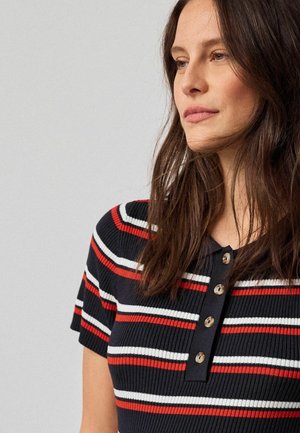 Ribbad pikétröja med korta ärmar i marinblått med röda och vita horisontella ränder. Har en knappslå med runda knappar i neutral färg.