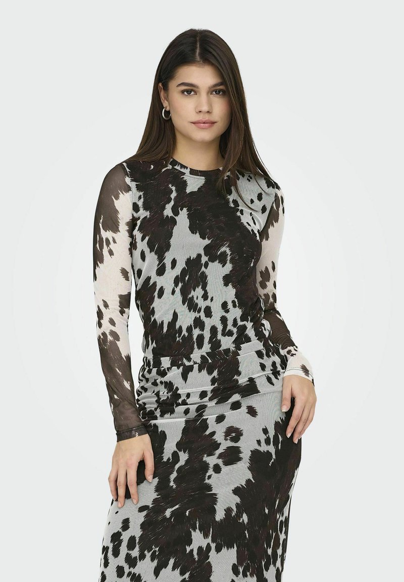 Haut à manches longues avec un motif vache noir et gris, fabriqué à partir d'un matériau texturé. Encolure côtelée et silhouette ajustée.