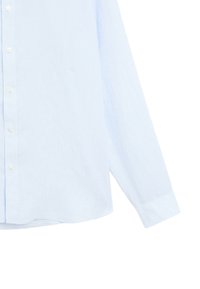 Chemise bleu clair à manches longues avec un seul poignet et des boutons blancs, montrée du milieu du torse jusqu'à la fin de la manche.