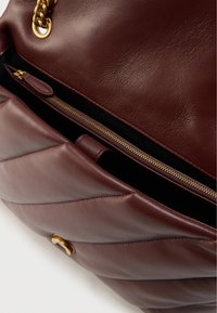 Χειροποίητη δερμάτινη τσάντα μπορντό με ραμμένο σχέδιο, χρυσά εξαρτήματα και θήκη με φερμουάρ. Διαθέτει ομαλή υφή και λουράκι αλυσίδα.