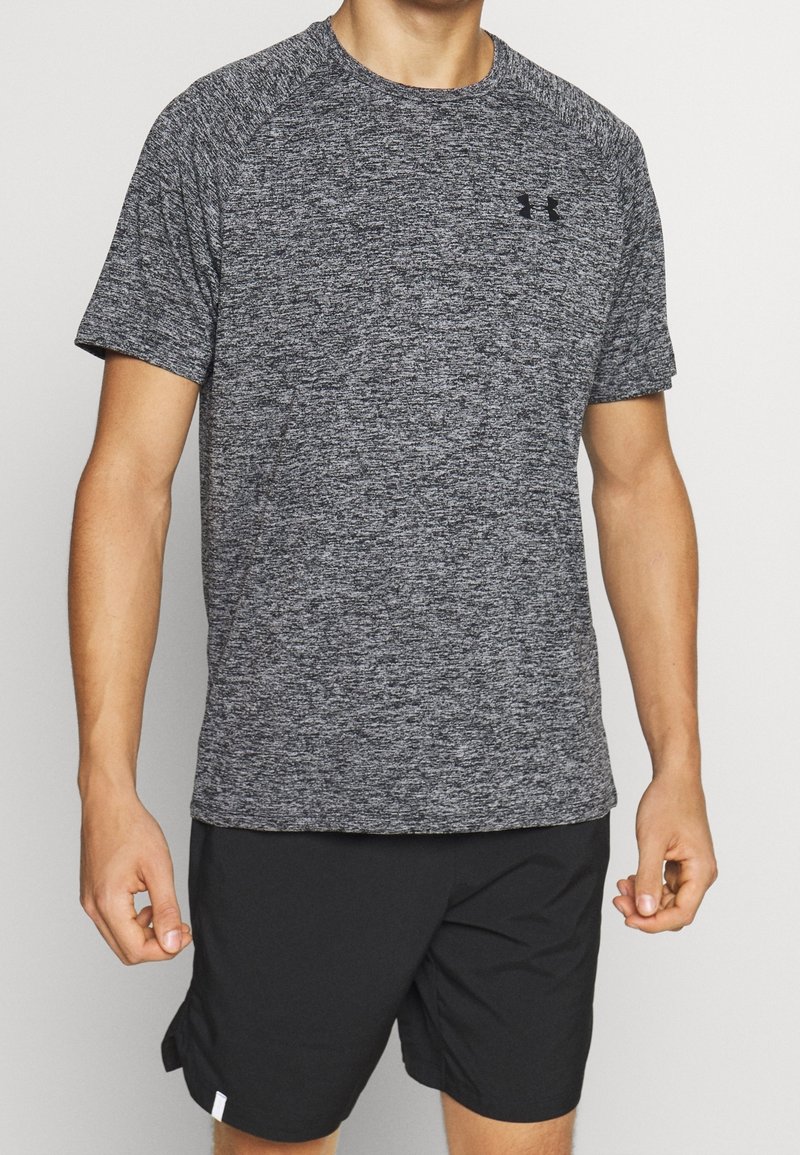 Grey heathered athletic t-shirt with short sleeves, round neck, and black logo on chest. Paired with black shorts. Fabric appears lightweight and breathable.