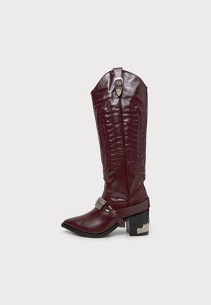 Botte de cowboy bordeaux montant jusqu’au genou, avec des surpiqûres décoratives, un bout pointu, des brides décoratives à boucles et un talon bloc noir.