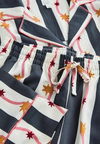 Loungewear sæt i navy og hvide striber med pink og gule stjernemønstre. Fremstillet af blødt stof med elastisk talje og snore.