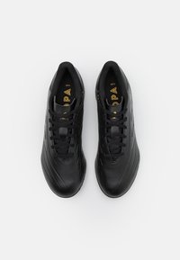 Zapatillas deportivas negras con parte superior de cuero texturizado, que cuentan con un diseño elegante, cierre de cordones y un sutil logotipo dorado en la lengüeta.